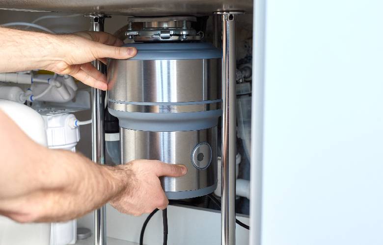 Een expert installeert een kleine waterontharder in een keukenkastje.