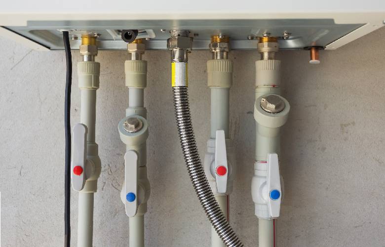 Vooraanzicht van de onderkant van een warmwaterinstallatie, aangesloten op een waterontharder van een appartement.